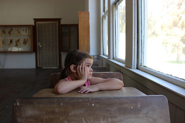 A schoolchild sat at their desk, looking wistfully out of the window